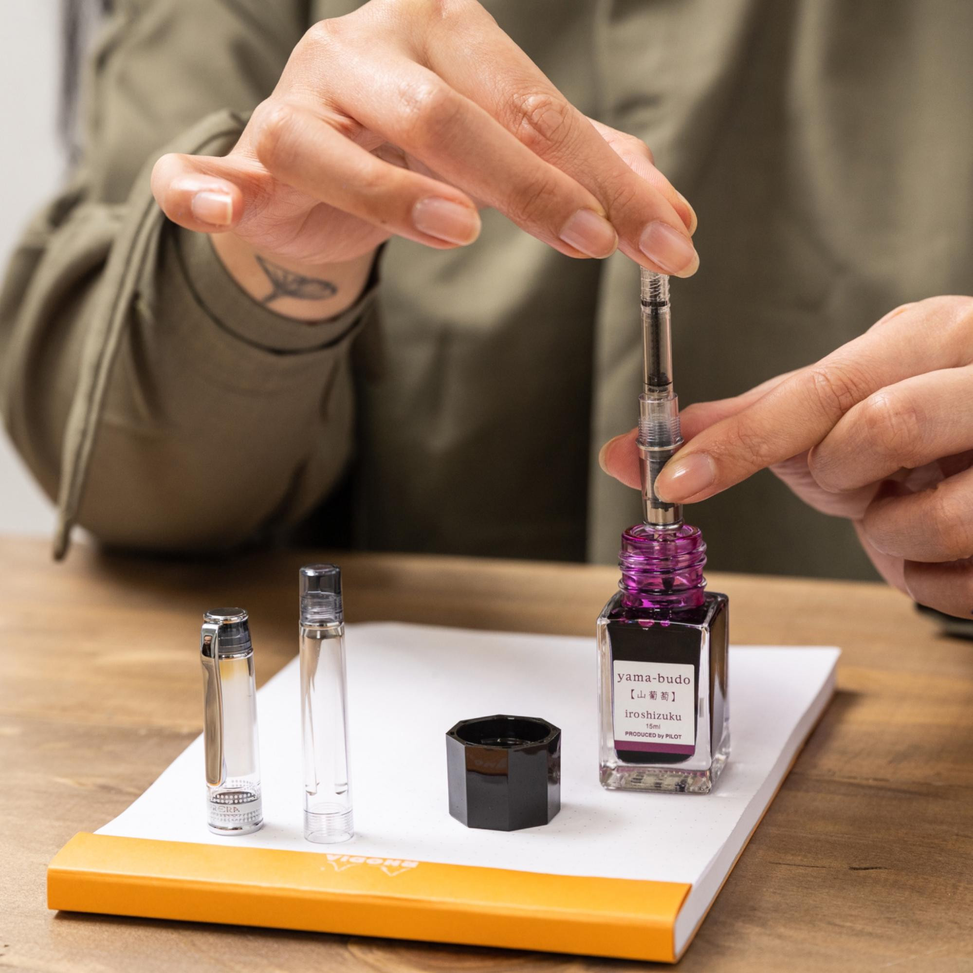 Close-up of a person refilling a quality pen with ink, demonstrating how good quality refillable pens reduce waste and offer the best writing experience.
