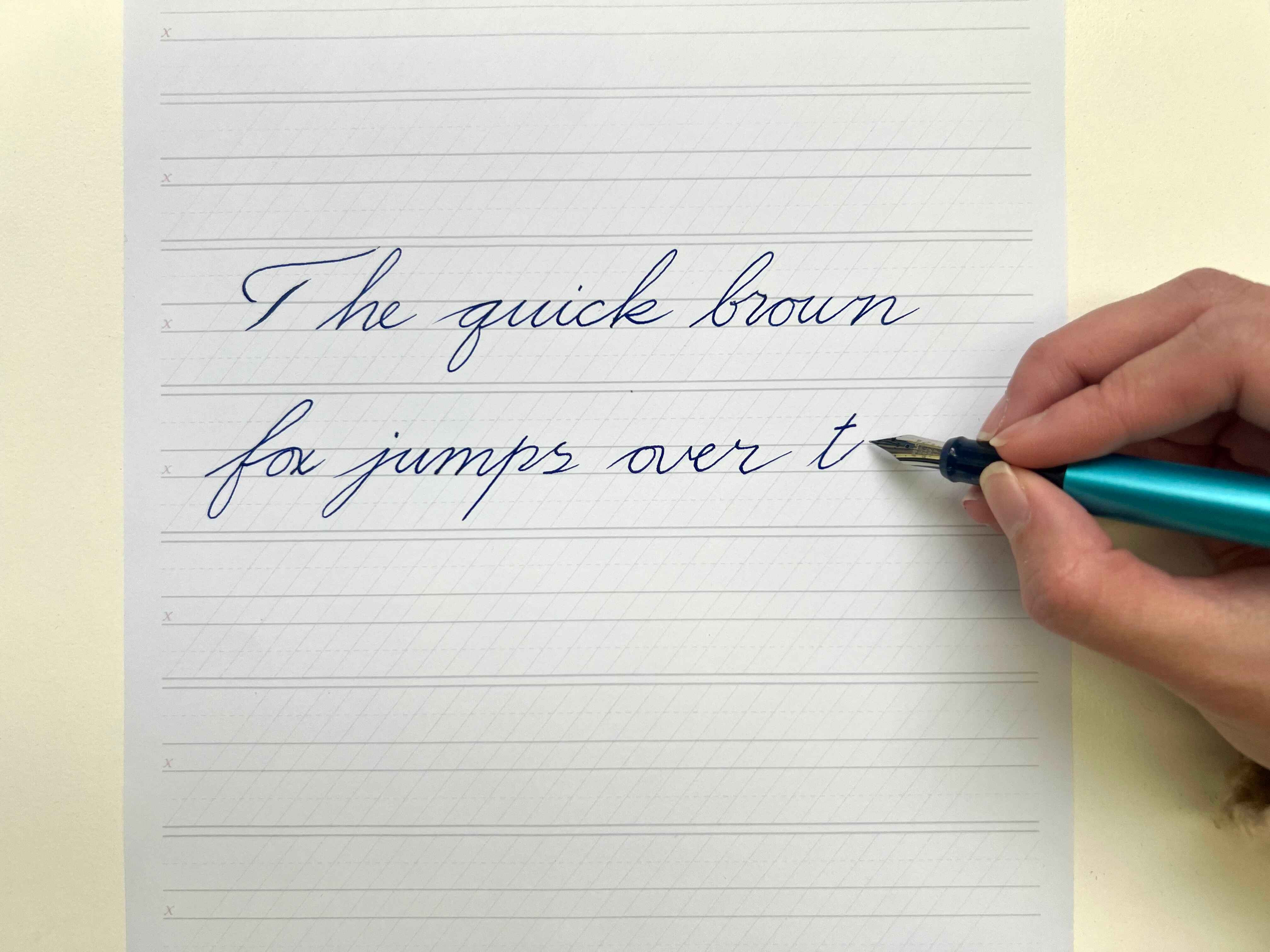 Woman practising fountain pen calligraphy, writing the words &ldquo;The quick brown fox jumps over t&hellip;&rdquo; 
