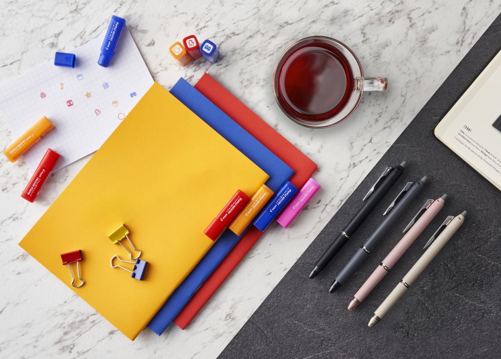 Flat lay of colourful notebooks, refillable pens, and stationery essentials, promoting a productive pen and paper workspace.