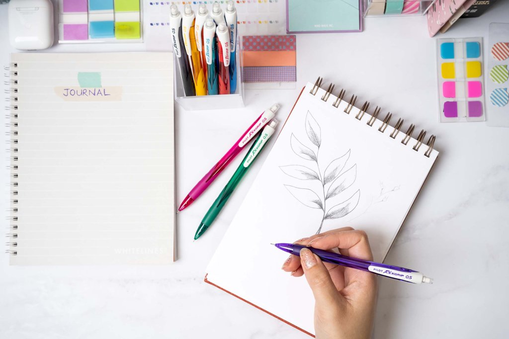 PILOT Pen BeGreen REXGRIP mechanical pencil 0.5 mm sketching a plant on a sketching pad with other pencils and a journal next to it.