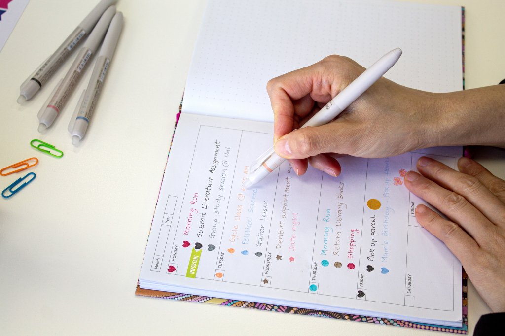 Handwriting in a weekly planner with colourful FriXion pens, one of the best pens for note taking and journaling.