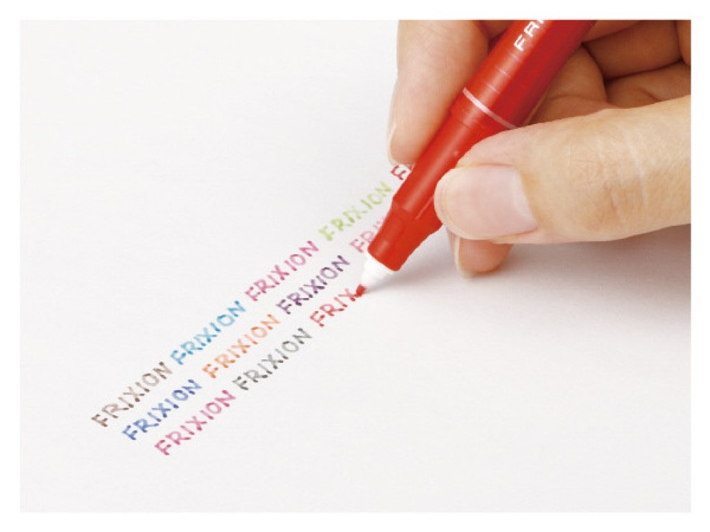 Hand using a red FriXion erasable pen to write colourful text, one of the best pens for note taking and journaling.