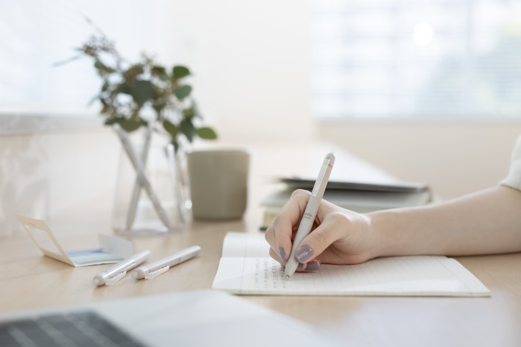 Hand writing in a notebook with a FriXion Waai pen, one of the best pens for note taking and journaling with a comfortable grip for everyday writing.