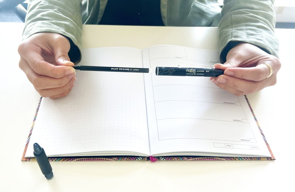 A person's hands refilling a blue FriXion clicker pen, pushing the new cartridge into the barrel.