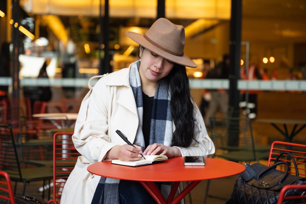 Woman practicing mindful writing at a caf&eacute; using a premium fountain pen.