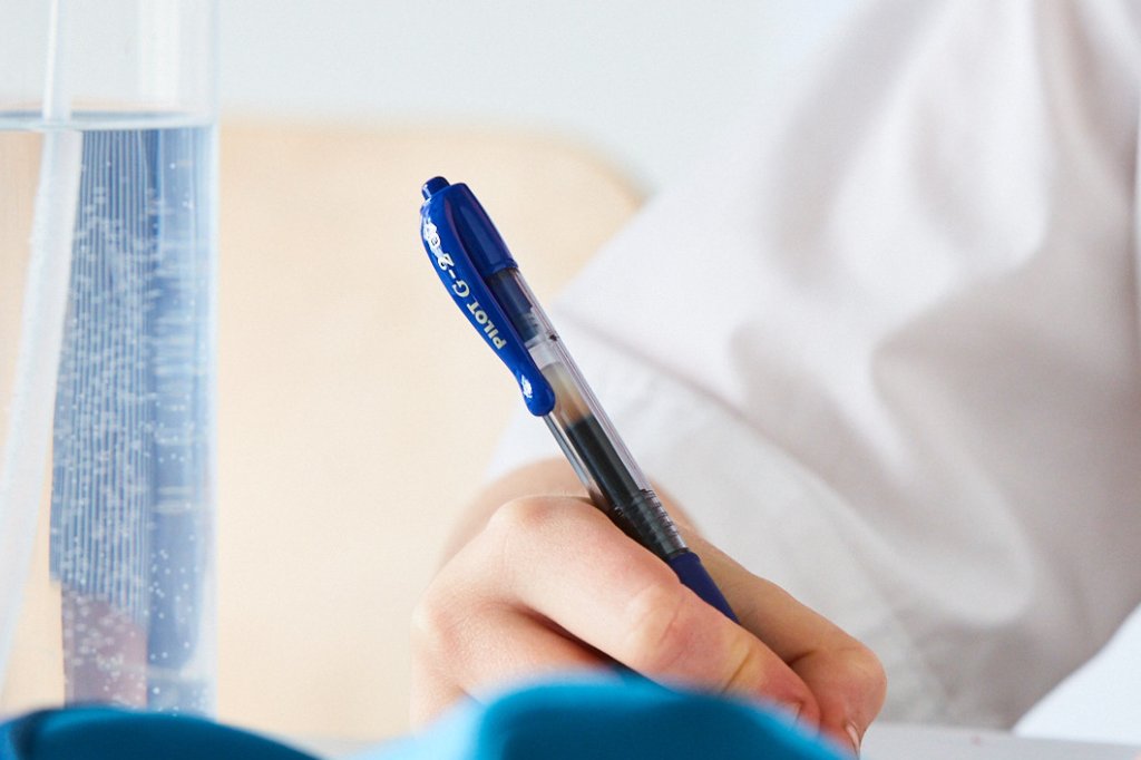 Primary school student writing with a Pilot G2 gel pen in a workbook.